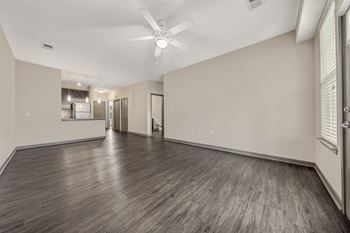 The living room and kitchen of a new home with white walls and wood floors